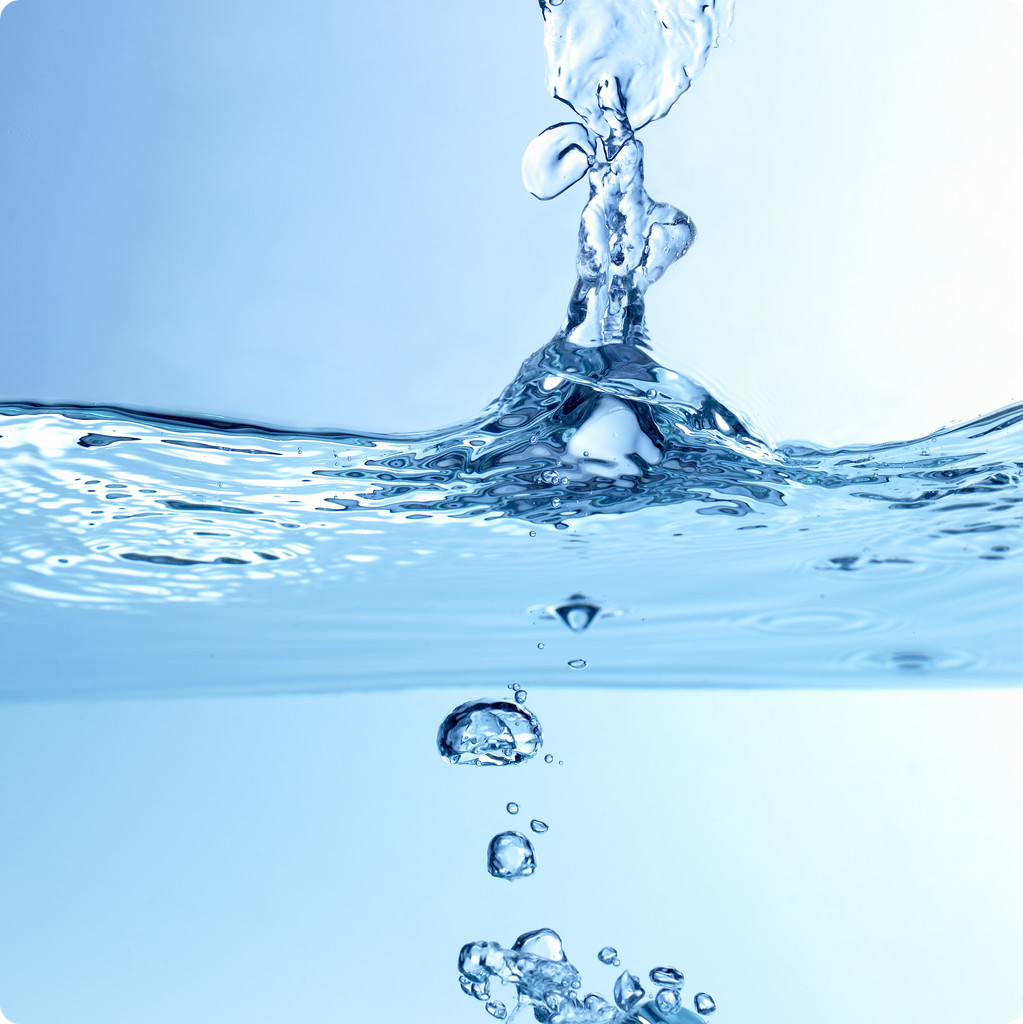 A drop of water plunges into a body of water creating a ripple effect.